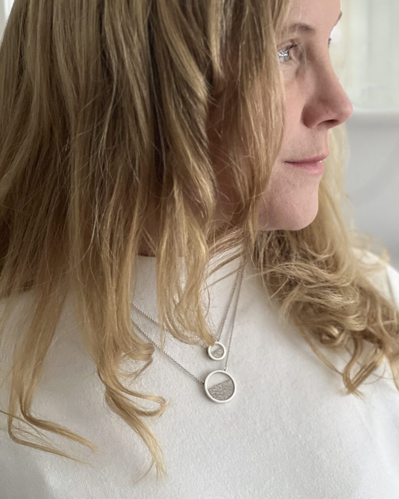 Woman wearing silver necklace holding sand